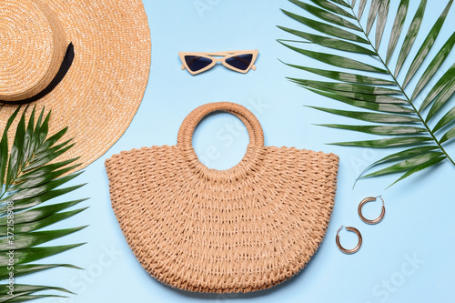 Wicker bag with hat and female accessories on color background