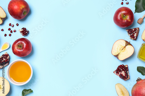 Honey, apples and pomegranates on light blue background, flat lay with space for text. Rosh Hashanah holiday