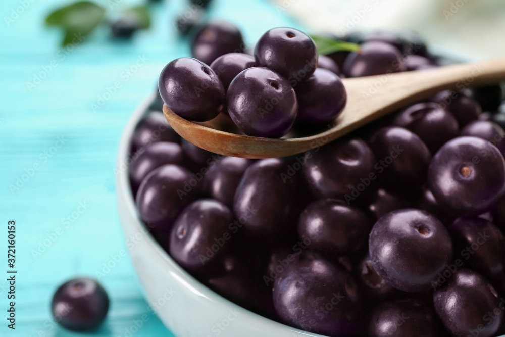 Tasty acai berries in bowl and spoon on table, closeup Tasty acai berries in bowl and spoon on table, closeup