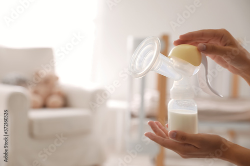 Closeup view of woman holding manual breast pump indoors, space for text. Baby health photo