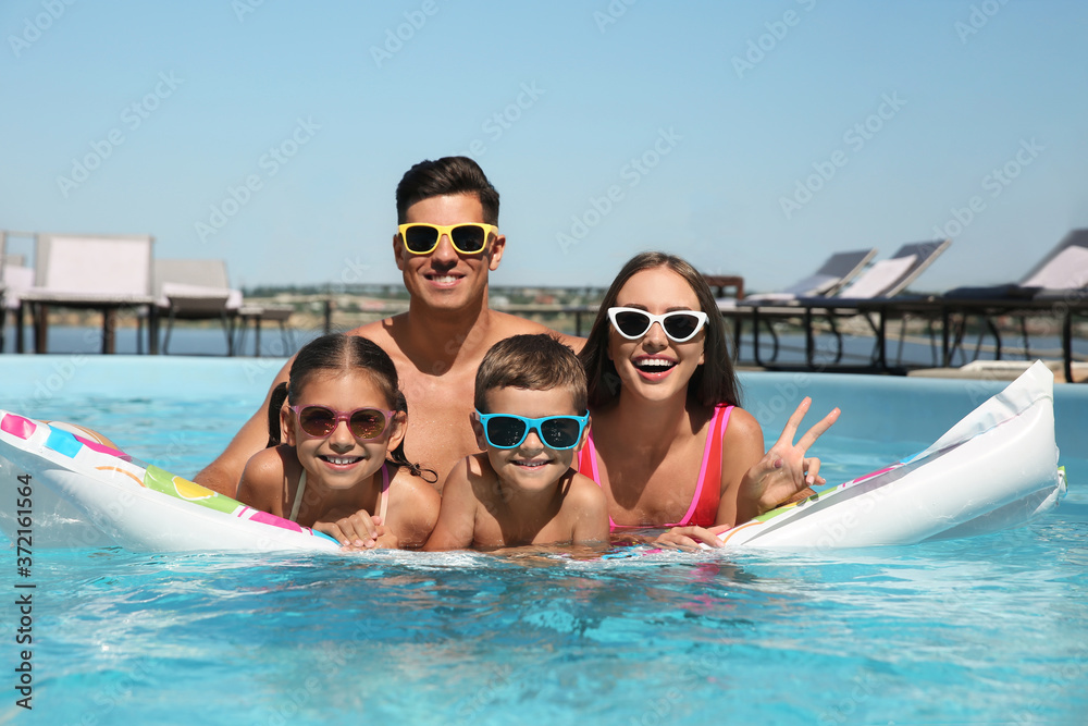 Happy family on inflatable mattress in swimming pool