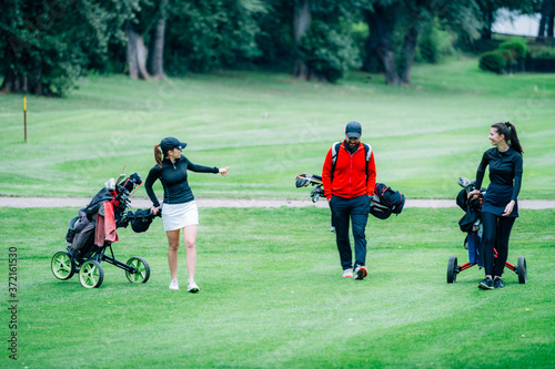 Golf training. Two young ladies with golf instructor having a lesson on a golf course