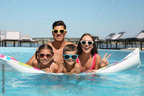 Happy family on inflatable mattress in swimming pool