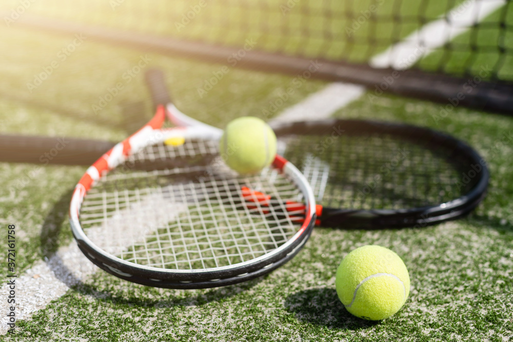 A tennis racket and new tennis ball on a freshly painted tennis court