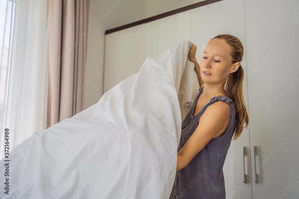 Young Female Housekeeper Changing Bedding In Hotel Room Young Female Housekeeper Changing Bedding In Hotel Room