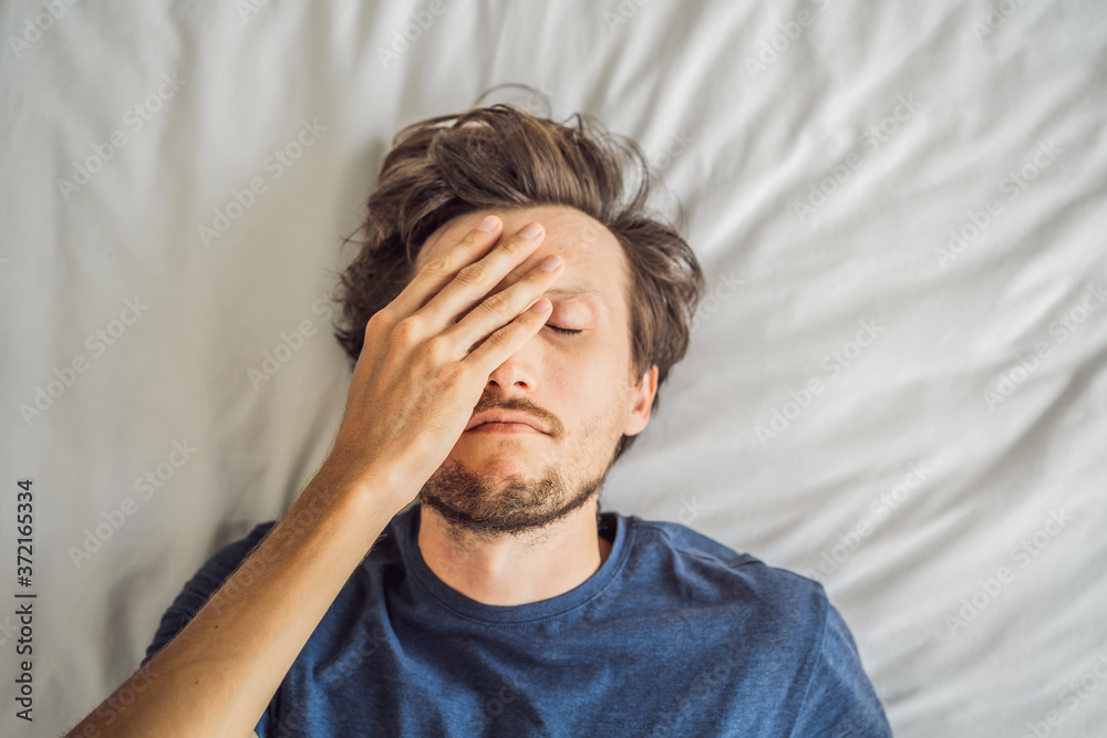 Extremly tired young man lying on the bed, home alone. self-isolation at home, quarantine due to pandemic COVID 19. Mental health problems in self-isolation at home