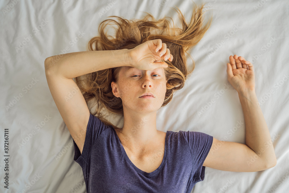 Fototapeta premium Extremly tired young woman lying on the bed, home alone. self-isolation at home, quarantine due to pandemic COVID 19. Mental health problems in self-isolation at home