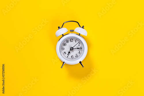White alarm clock on yellow background