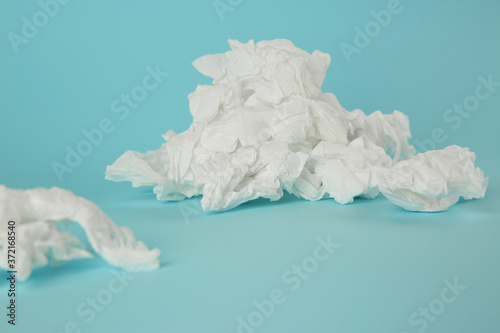 Used paper tissues on light blue background, closeup photo