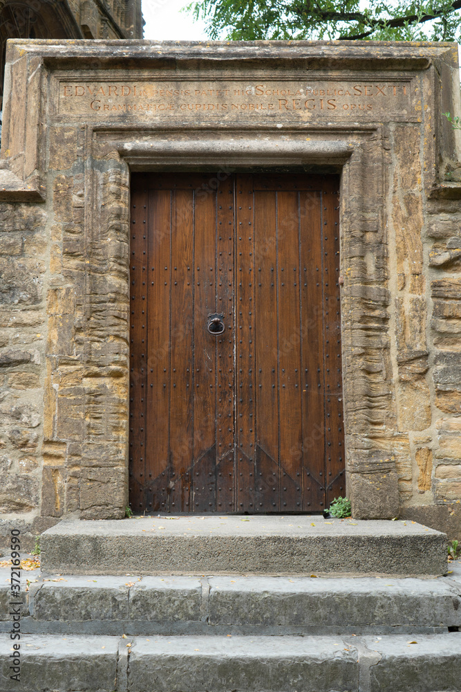 Old traditional heavy set wooden door with large stone arch around it and steps leading up to it. Old traditional heavy set wooden door with large stone arch around it and steps leading up to it.