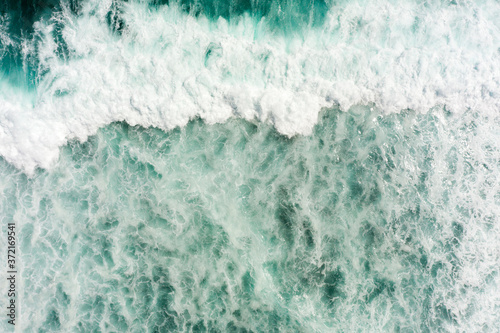 Top aerial view of giant ocean waves crashing and foaming.