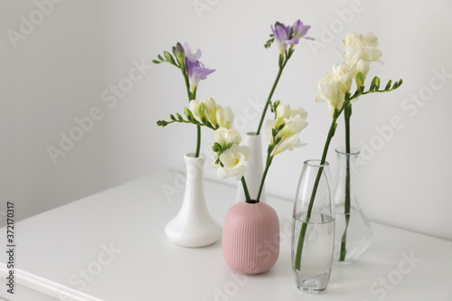 Beautiful spring freesia flowers on white table in room