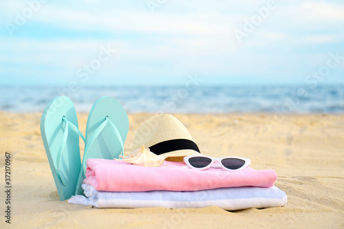 Different stylish beach objects and seashell on sand near sea