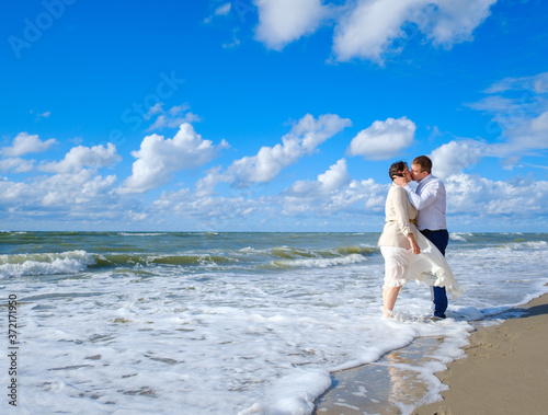 Happy bride and groom hugging on beach