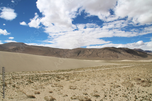 View of the mountain and sand dune with dirt road near Tingri on the way to Everest Base Camp, Tibet, China