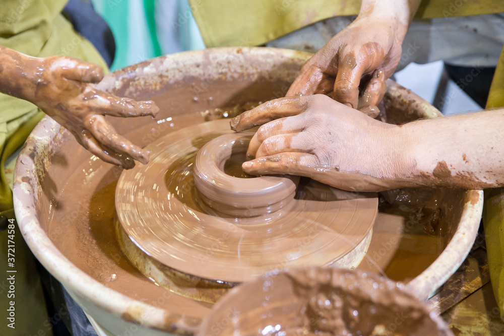 Hands on a pottery wheel. Potter hand. Clay potter creating on the pottery wheel