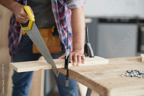 Carpenter cutting block of wood using hand saw photo