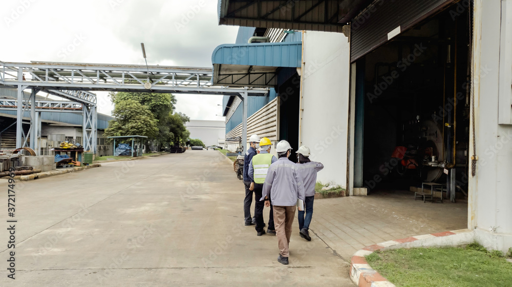 Engineers are walking through industry manufacturing factory, Safety patrol in manufacturing area, Cooperation by engineer and technician to check abnormality in factory