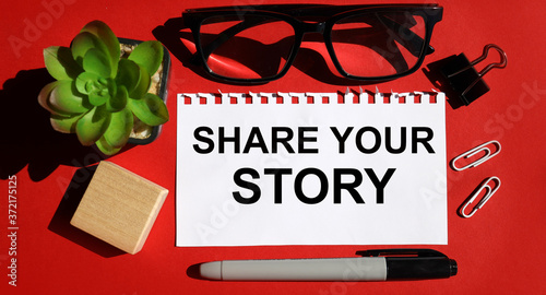 share your story word. TEXT is written on white paper on a red background near the stationery.