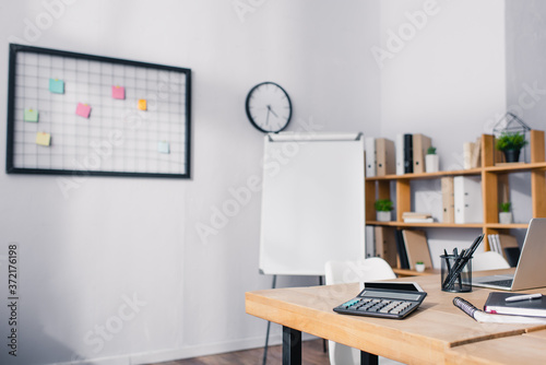 Selective focus of calculator, stationery and digital devices on wooden table in white office © LIGHTFIELD STUDIOS