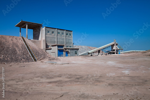 Mynaral, Kazakhstan: Modern Jambyl Cement plant mineral chalk quarry. Industrial building and transporter on clear blue sky.