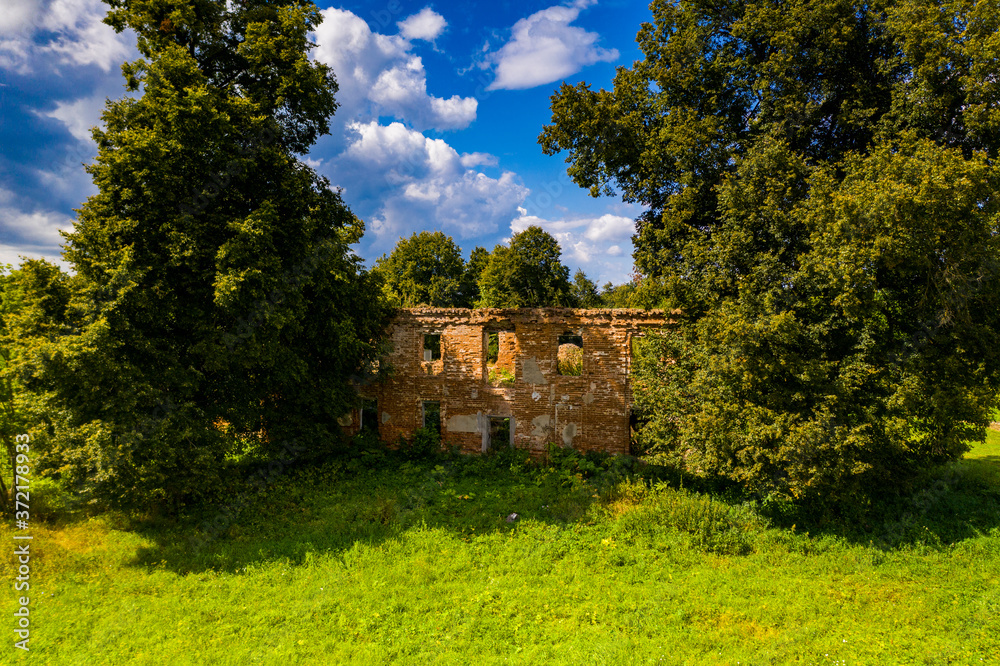 an old manor house turned into ruins of red brick and a church removed from a drone an old manor house turned into ruins of red brick and a church removed from a drone