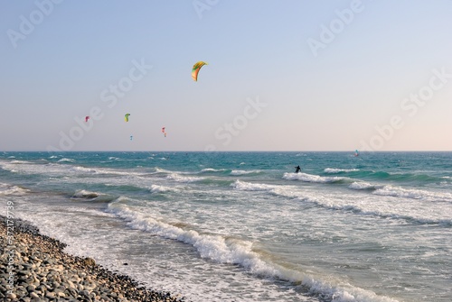 Kitesurfers on a windy day with foamy waves crashing the Kourion beach near Limassol, Cyprus