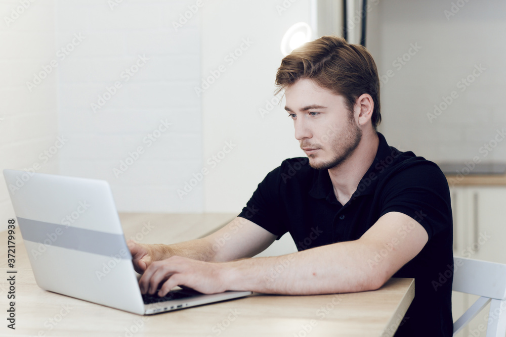 Young man working at home, typing on laptop sitting at desk. Work at a distance during quarantine of coronavirus. Stay at home, self-isolation Young man working at home, typing on laptop sitting at desk. Work at a distance during quarantine of coronavirus. Stay at home, self-isolation
