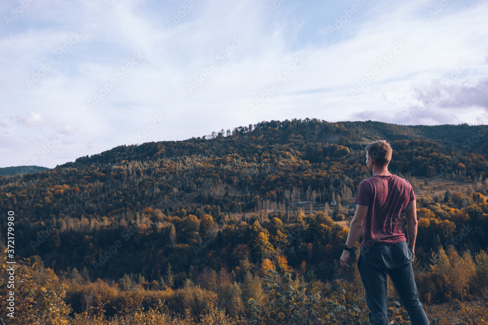 man looking at autumn forest mountains