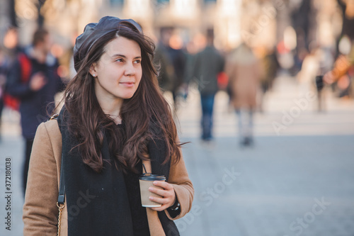 portrait of stylish gorgeous woman in coat outdoors drinking coffee to go