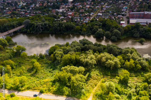 a panoramic view from a drone of a dark river and green trees around in summer © константин константи
