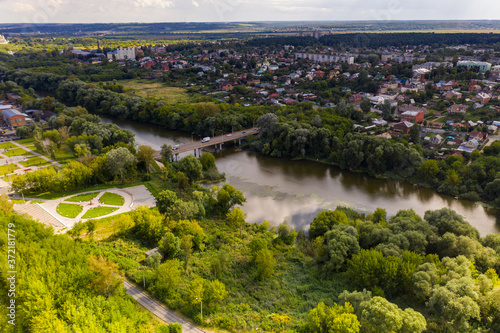 a panoramic view from a drone of a dark river and green trees around in summer
