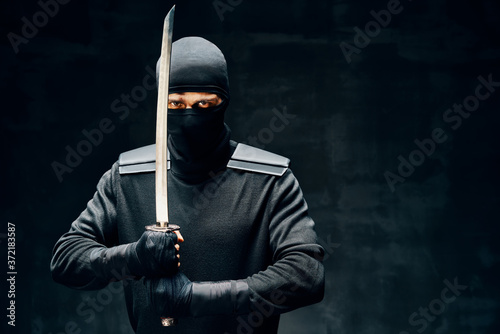 Fighting ninja with a sword over black background