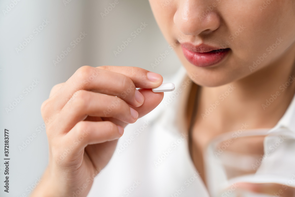 Woman taking medicine and holding a glass of water in hand, Because there is an illness. Woman taking medicine and holding a glass of water in hand, Because there is an illness.