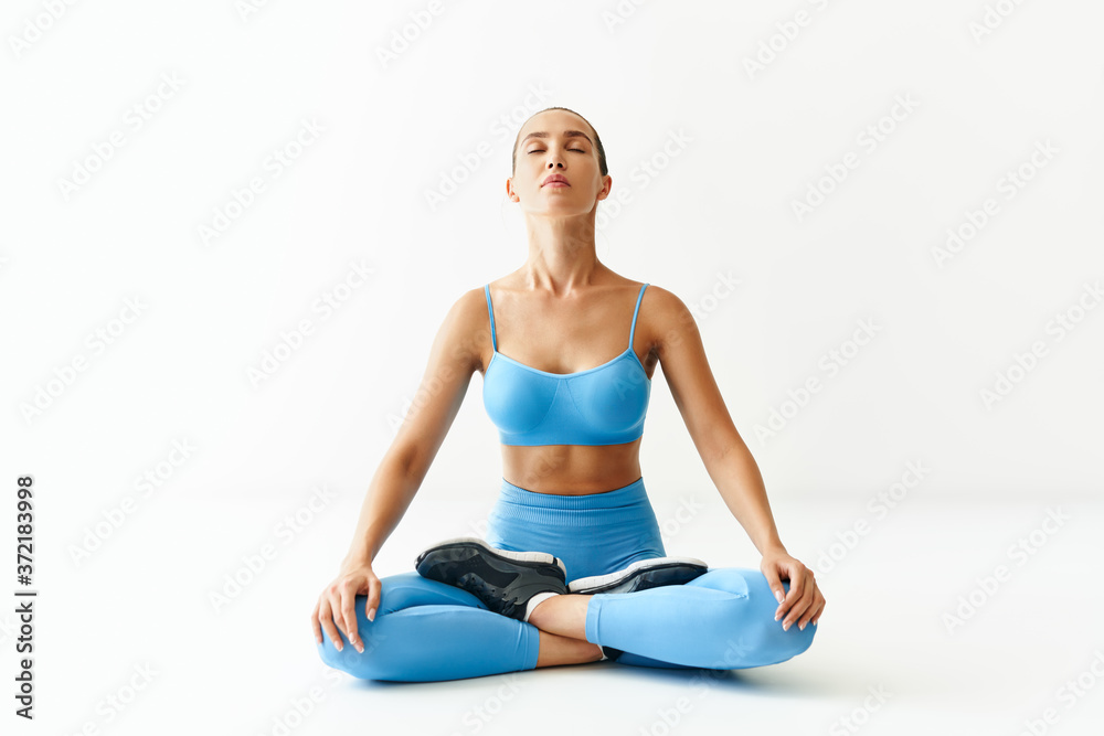 Young sporty attractive woman in sportswear practicing yoga, meditating in Lotus pose Padmasana