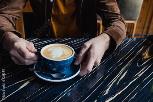 Close-up of man hand having a cup of cappuccino