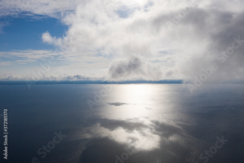 Aerial view clouds over the sea. View seashore and coastline from drone. Aerial top view cloudscape. Texture of clouds. View from above. Sunrise or sunset over clouds. Aerial ocean background
