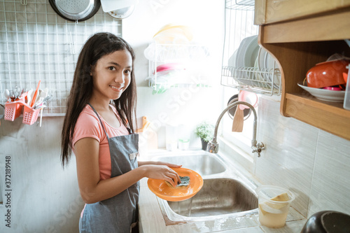 teenage girls happily do the household chores washing dishes doing activities during the pandemic at home