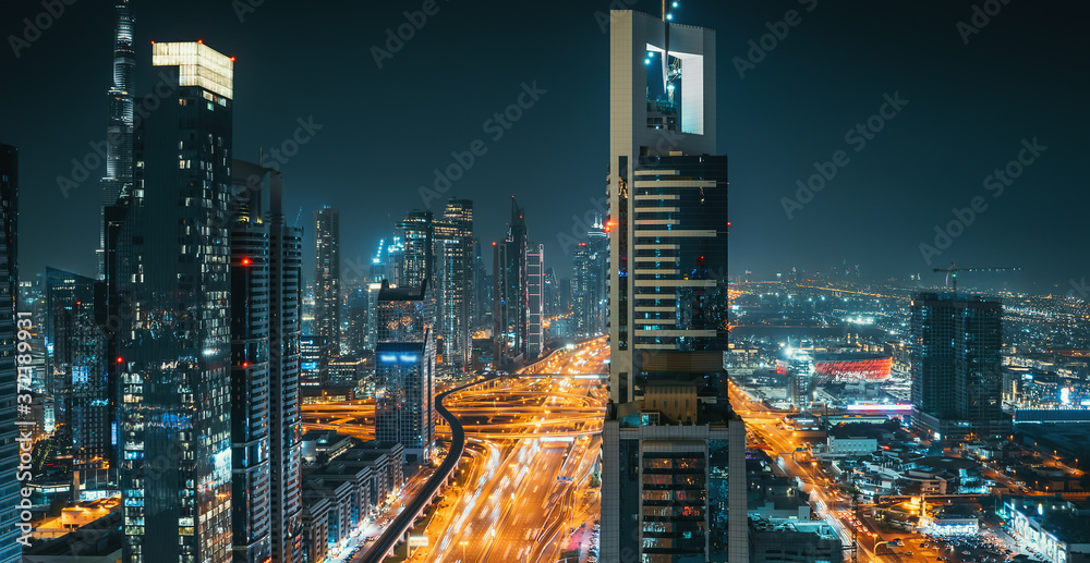 Dubai downtown night panorama with modern buildings and illuminated roads, luxurious travel and tourism, UAE.