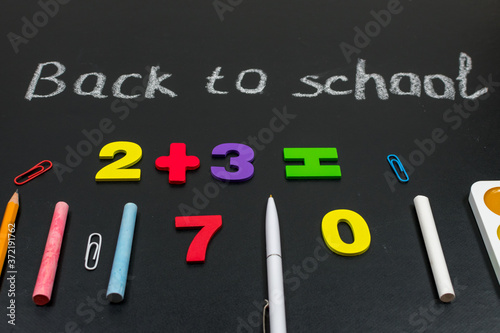 Multicolored colorful numbers, counting sticks, math signs on a chalkboard. Back to school. Concepts. School supplies on a chalkboard. View from above.