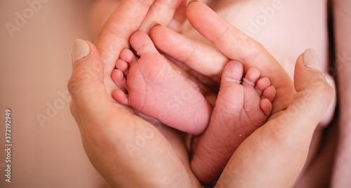 Baby feet in mother hands. Tiny Newborn Baby's feet on female Heart Shaped hands closeup. Mom and her Child. Happy Family concept. Beautiful conceptual image of Maternity. © Inception