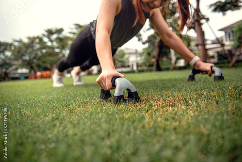 Fitness training outdoor, Healthy lifestyle concept. Closeup - Sport woman doing crossfit push ups in the park. © oatawa