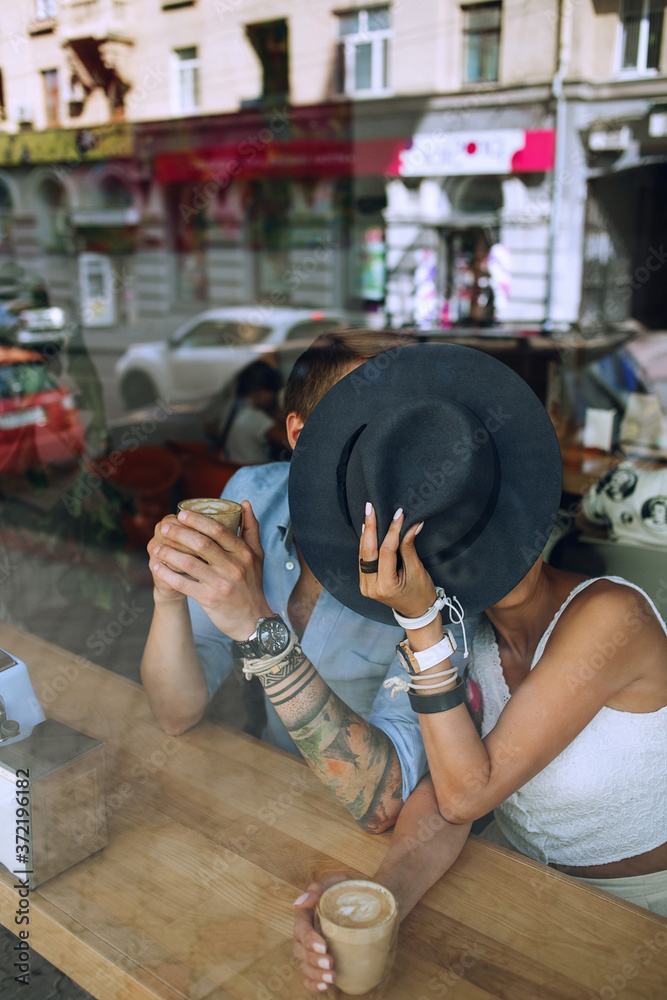 Couple hiding behind hat in cafe