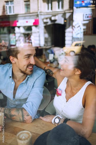 Joyful couple talking in cafe behind the window