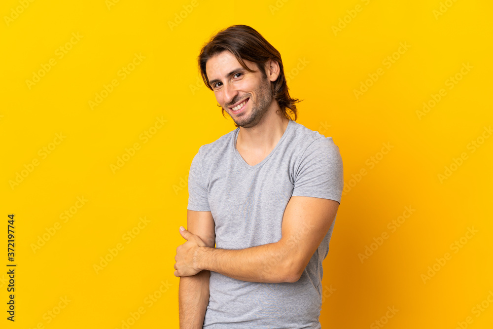 Young handsome man isolated on yellow background laughing Young handsome man isolated on yellow background laughing