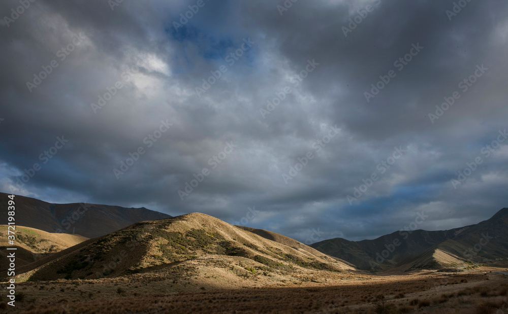 Dramatic landscape with Clouds. Otago. Lindis Pass near Cromwell. New Zealand. Sunset.