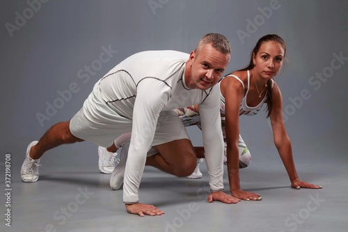 Young sports couple engaged in fitness on a gray background