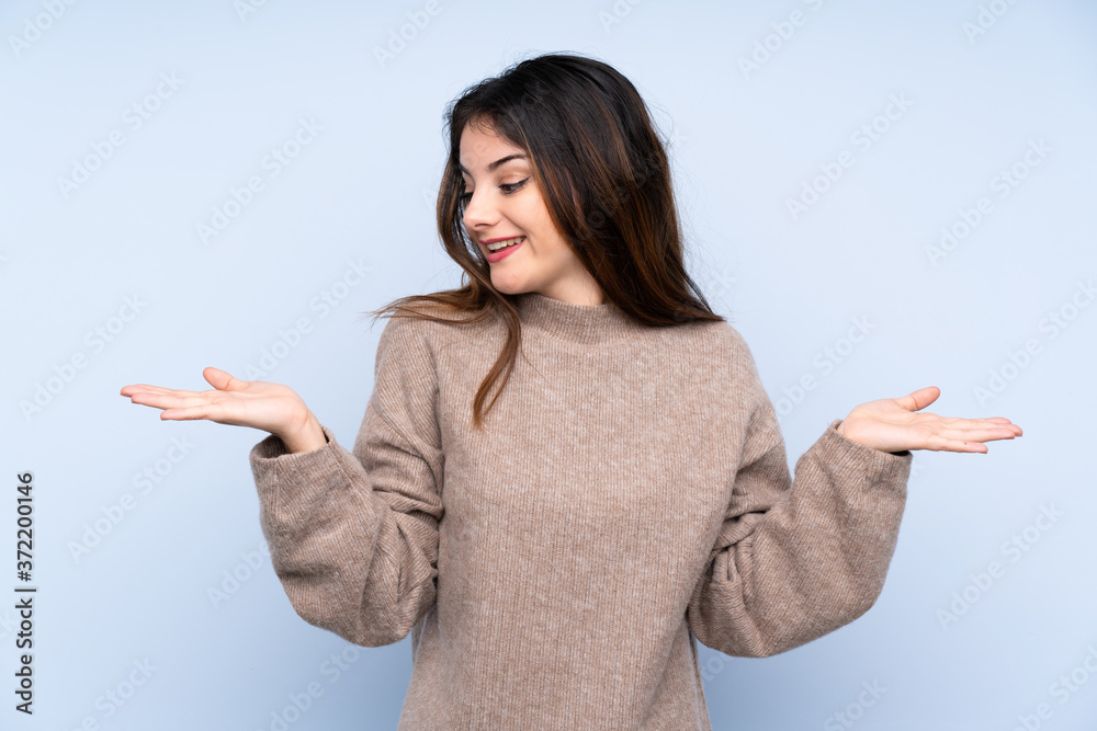 Young brunette woman wearing a sweater over isolated blue background holding copyspace with two hands Young brunette woman wearing a sweater over isolated blue background holding copyspace with two hands