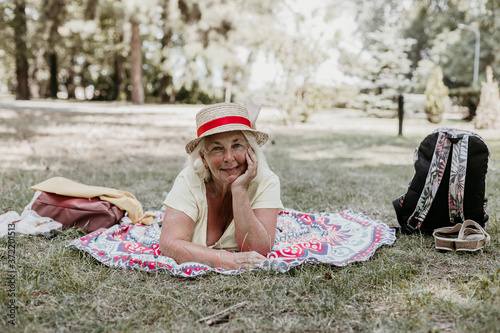 Beautiful blond smiling happy woman in a straw hat relaxing on a blanket at a picnic in the park © Shi 