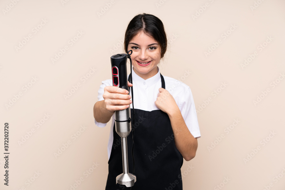 Young woman using hand blender over isolated background with happy expression Young woman using hand blender over isolated background with happy expression